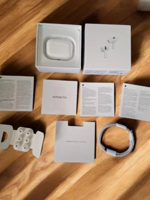 Apple AirPods Pro 2 nd generation  med laddningsetui - Säljer ett par Apple AirPods Pro 2 nd med vitt laddningsetui. Hörlurarna är trådlösa in-ear och levereras med flera silikonpluggar, laddningskabel och originalförpackning. Snygg och stilren design i vitt, perfekt för dig som vill ha grymt ljud och smidig anslutning till Apple-enheter. De är helt nya alltså 100% nytt skick