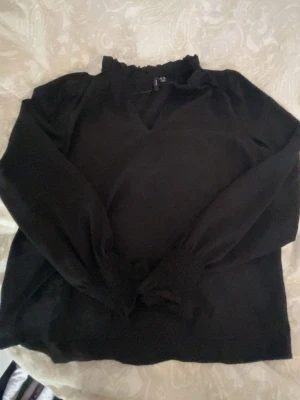 Svart blus med volangkrage Vero Moda - använd 1-3 gånger!! Svart blus från Vero Moda i storlek XS. Blusen har lång ärm med resår vid ärmslut och en söt volangkrage med liten knytning. Tunt och lätt material som ger en luftig känsla. Perfekt att styla med jeans eller kjol.