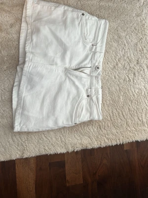 Vita denimskorts från D62 - Snygga vita skorts i denim från D62 med klassisk femficksdesign, dragkedja och knapp framtill samt bälteshällor. Skortsen har två bakfickor och är tillverkade i ett stadigt bomullsmaterial. Perfekta för en fräsch och trendig look. Helt nya och har inte använt dem !!!