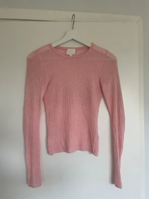 Rosa ribbstickad tröja från H&M - Säljer en ljusrosa ribbstickad tröja från H&M. Använd ett fåtal gånger och säljer endast för att den är lite för liten på mig. Den är lite genomskinlig så man kan ha ett linne under eller bara bh.