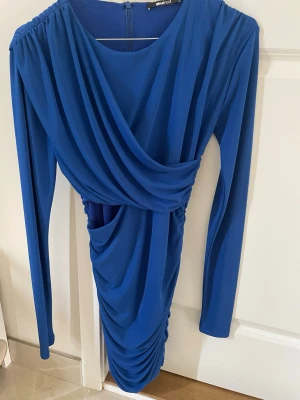 Blå draperad klänning  - Säljer en blå kortklänning från Gina tricot skön i materialet 