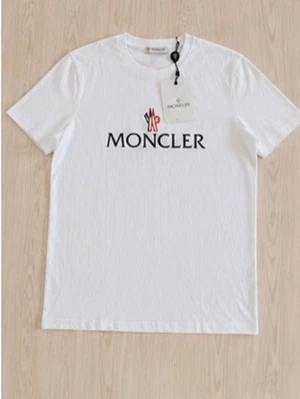 Vit Moncler t-shirt med logga - Snygg vit t-shirt från Moncler med klassisk logga i svart, rött och blått framtill. T-shirten har rund halsringning och korta ärmar. Tillverkad i mjuk bomull för en bekväm känsla och stilren look.