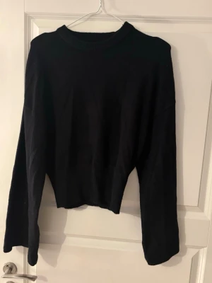 Svart stickad tröja med vida ärmar - En svart stickad tröja med rund hals och vida, långa ärmar. Mjuk stickad. Lite croppad. Säljer för 150kr + frakt