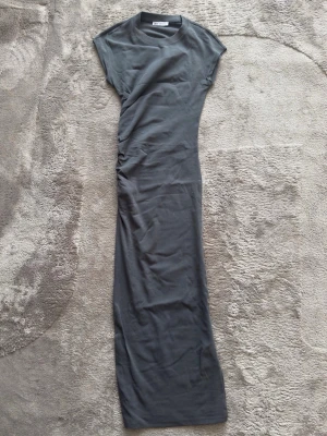 Grå långklänning från Zara - Snygg grå midiklänning från Zara med rund halsringning och korta ärmar. Klänningen har en figurnära passform och är tillverkad i mjuk bomull, perfekt för en stilren look.