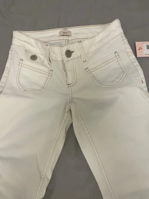 Vita bootcut jeans från Nelly - Snygga vita bootcut jeans från Nelly med hög midja och klassiska fem fickor. Jeansen har kontrastsömmar och stängs med knapp och dragkedja. Perfekta för en clean och trendig look. Köpte för 699 men säljer för 550. Pris går att diskutera vid snabb köp.