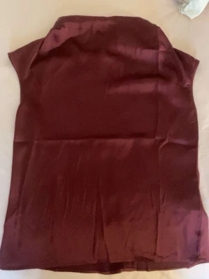 Vinröd ärmlös satintopp ifrån hm💓 - Jag säljer en vinröd blus i glansigt satinmaterial med ärmlös design och liten krage. Blusen har en enkel och stilren look med knapp i nacken. Den är ifrån hm, i storlek xs💓💓