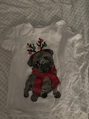 Vit t-shirt med julig mops💓 - Vit t-shirt med tryck av en söt mops som har renhorn och röd halsduk. Perfekt för dig som älskar hundar och vill ha en rolig julig look. Klassisk passform och korta ärmar. Materialet känns mjukt och bekvämt.❤️❤️🎅🏼🐶