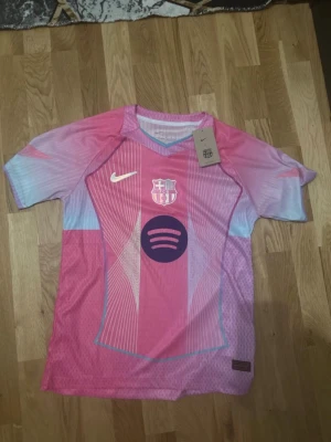 FC Barcelona rosa matchtröja Nike - Säljer en FC Barcelona matchtröja från Nike i rosa och ljusblått med vita detaljer. Tröjan har klubbmärke, Nike-logga och Spotify-logga på bröstet. Tillverkad i lätt och ventilerande material, perfekt för fotbollsträning eller support.