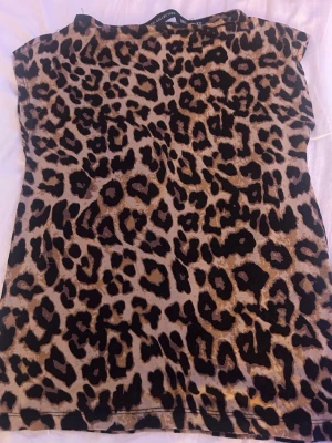 Leopardmönstrad topp XS Black Label - Snygg leopardmönstrad topp från lager 157  i storlek XS. Toppen har klassisk rund halsringning och är ärmlös, perfekt för dig som vill sticka ut med ett djuriskt print. Materialet känns mjukt och följsamt mot huden.