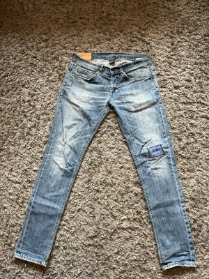 Dondup George  - Säljer ett par ljusblå skinny jeans med slitningar och en blå patch på höger knä. Jeansen har klassisk femficksdesign, låg midja och dragkedjegylf. Perfekta för en avslappnad och trendig look. W33 skinny fit.