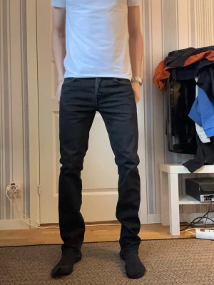 Svarta slim fit jeans - Snygga svarta slim fit jeans med klassisk femficksdesign och raka ben. Jeansen har bälteshällor och subtila sömmar. Perfekta för en stilren och enkel look. Materialet är troligtvis bomull med stretch för extra komfort.