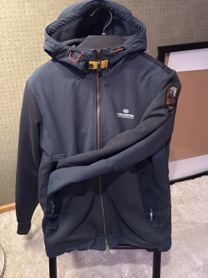 Parajumpers Cardigan/vindjacka - Snygg mörkblå vindjacka från Parajumpers med huva, dragkedja framtill och två fickor med dragkedja. Den är 100% riktig som man ser på Sista bilden.