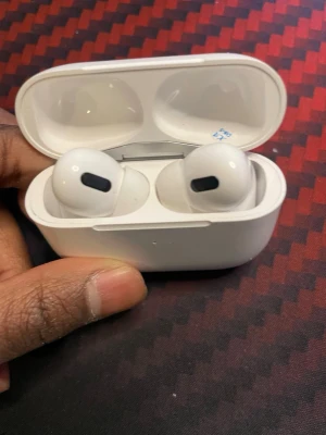Hörlurar från okänt märke med laddningsetui - Säljer ett par vita hörlurar med tillhörande laddningsetui. Hörlurarna har en stilren och kompakt design i blankt plastmaterial och är trådlösa med in-ear passform. Perfekta för musik, samtal och gaming.
