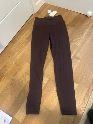 Bruna leggings med hög midja - Snygga bruna leggings med hög midja och scrunch-detalj bak. Stretchigt material som sitter tight och bekvämt. Perfekta till en avslappnad look eller när du vill känna dig extra bekväm. Långa ben och enkel design utan synliga loggor.