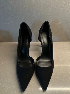 Svarta Mango klackar  -  Klassiska svarta Mango klackar med spetsig tå och smal klack. Ett måste i garderoben – passar lika bra till kontoret som till fest.  Fint skick och sparsamt använda. Stilren design som aldrig går ur mode.