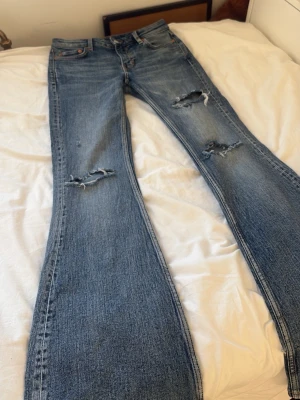 Blå bootcut jeans - Säljer ett par blå bootcut jeans från weekday med hål på låren och knäna. Jeansen har lite slitningar längst ner ( bild 3). 💞 SKRIV OM FRAKT