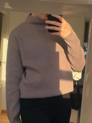 Ljusbrun croppad stickad tröja - Säljer en ljusbrun finstickad tröja med hög hals och långa ärmar. Tröjan är endast använd vid ett tilfälle som ny.