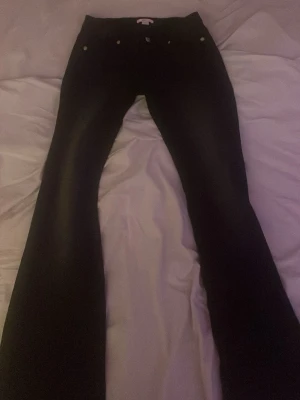 Svarta bootcut jeans - Snygga svarta bootcut jeans med klassisk femficksdesign och normal midja. Jeansen har en lätt utsvängd passform nedtill och är tillverkade i denim. Perfekta för dig som gillar en tidlös och stilren look.