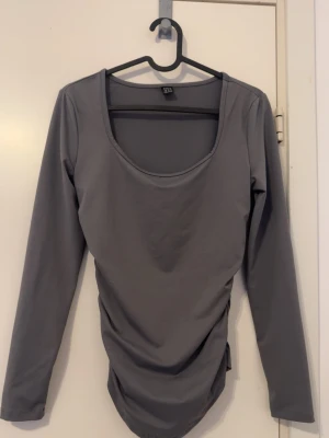 Grå långärmad topp med rynkade detaljer - Snygg grå långärmad topp, passar perfekt om du vill ha en stilren look, sitter jätte fin på kroppen, har bara använt 1 gång