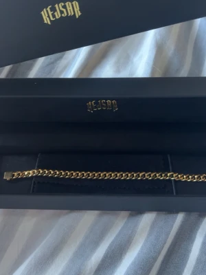 Guld länk från Kejsar - Snyggt guldfärgat armband från Kejsar med klassisk kedjedesign. Armbandet har en stilren och tidlös look, perfekt för att lyfta din outfit. Levereras i original ask med Kejsar-logga.