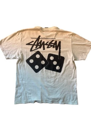 Vit Stüssy t-shirt - Vit t-shirt från Stüssy med riktigt snyggt tryck på ryggen, använts sparsamt under förra sommaren och har inga särskilda slitningar eller fläckar. För fler frågor skriv jätte gärna till mig!😊(Garanterad äkthet)✅