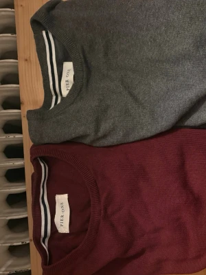 Grå och vinröd tröja från Pier One - Två stilrena, en grå och en vinröd tröja från Pier One med rund halsringning och ribbade muddar. Perfekt för lager-på-lager och enkel att matcha med andra plagg. Materialet känns mjukt och bekvämt mot huden. De är båda i S/M dvs att de passar båda storlekarna. Postar snabbt.