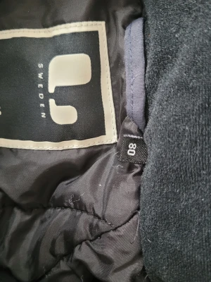 Svart overall från Lindberg strl 80 - Mörkblå/svart overall från Lindberg i storlek 80. Overallen har reflexdetaljer på rygg och ärm samt resår i midjan för bättre passform. Materialet är slitstarkt och vattenavvisande, perfekt för utomhuslek under kalla dagar.