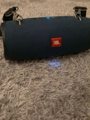 JBL xtreme 2 bärbar högtalare  - Säljer en JBL bärbar högtalare i blått tygmaterial med svart plast på sidorna. Högtalaren har en cylinderformad design, tydliga knappar på ovansidan och en axelrem för enkel transport. Perfekt för att ta med sig musiken överallt.