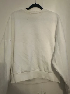 Vit oversized sweatshirt - En enkel och clean vit sweatshirt i oversized modell. Tröjan har rund halsringning, långa ärmar och ribbade muddar vid ärmslut och nederkant. Perfekt för en chill och avslappnad stil. Materialet känns mjukt och bekvämt mot huden.