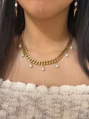 Guldpläterat  18k, 9 mm bred halsband med  pärlor - Presentask ingår. Det finns möjlighet att köpa utan preesentask till ett lägre pris (se en annan annons på min sida).                        Elegant halsband i guldpläterat rostfritt stål  från Diavansa– finns även i silverfärgad variant. Matchande örhängen finns i en separat annons.  Smycket är 9 mm brett och har en justerbar längd mellan 42 + 6 cm, vilket gör att det passar perfekt oavsett stil och tillfälle.. De nickelfria och handgjorda 