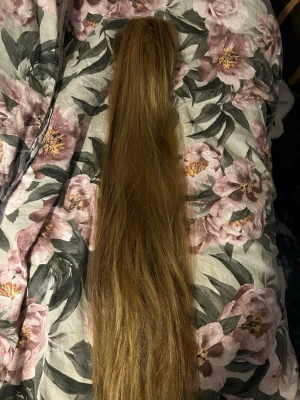 Lång blond hårklämma med löshår - Snygg hårklämma med långt, blont löshår. Perfekt för att snabbt fixa en fyllig hästsvans eller ge extra volym till din frisyr. Klämman är i brun plast och håret är rakt och naturligt fallande. Passar dig som vill ha en enkel och stilren håraccessoar.