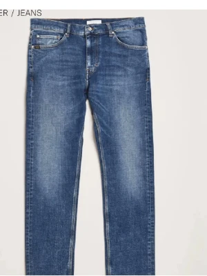 Blå raka jeans från Tiger of Sweden - Säljer ett par klassiska blå jeans från Tiger of Sweden med raka ben och femficksmodell. Jeansen har snygga slitningar och kontrastsömmar samt en läderpatch med logga bak i midjan. Perfekta till en avslappnad stil. Storlek 30/32.