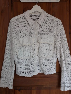 Vit spetsmönstrad skjorta - Säljer en vit virkad skjortjacka med blommigt hålmönster. Superfint skick då jag endast använt den några enstaka gånger 💖🌷