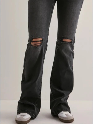 Svarta bootcut jeans med slitningar - Säljer ett par svarta bootcut jeans med slitna detaljer över knäna. Jeansen har en klassisk femficksmodell och är tillverkade i denim med lätt stretch. Perfekta för en avslappnad och trendig look.