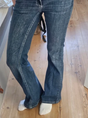 Blå bootcut jeans med utsvängda ben / Low Waist Bootcut Stitch Jeans - Säljer ett par klassiska blå bootcut jeans med utsvängda ben och normal midja. Jeansen har en snygg tvätt och kontrastsömmar längs benen. Perfekta för dig som gillar retrostil och vill ha ett par jeans som sticker ut lite extra. Jag är 172 och de nuddar precis marken.