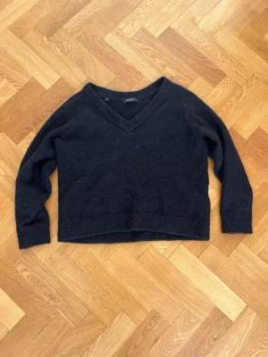 Svart stickad tröja från Selected Femme - Mysig svart stickad tröja från Selected Femme med v-ringning och lång ärm. Storleken är L men den passar som en S, krympt i tvätten!