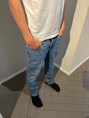 Jack and Jones  - Säljer ett par blå Jack and Jones jeans som har bra passform och normal midja. Jeansen har fem fickor, dragkedjegylf och är tillverkade i klassisk denim. Perfekta för en avslappnad och stilren look. Modellen i bild är 184cm