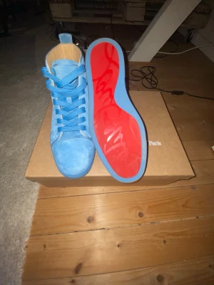 Blåa Christian Louboutin sneakers - Kommer tvätta dom innan jag skickar det ända är lite smuts på sulan som är enkelt att ta bort! > Snygga blåa high top sneakers från Christian Louboutin i mocka med ikonisk röd sula. Skorna har matchande blå skosnören och en rund logga på sidan. Perfekta för dig som vill sticka ut med exklusiva detaljer och unik färg.