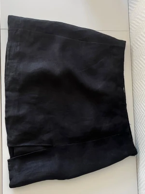 Svart kortkjol  - Stilren svart kortkjol med slits framtill. Kjolen har en enkel, rak passform. 