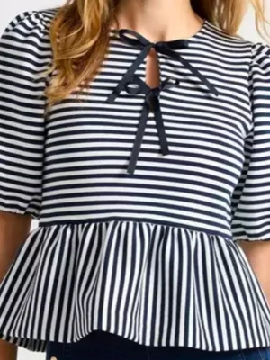 Randig blus med knyt från Holly & White - Snygg blus från Holly & White med marinblå och vita ränder, puffärm och volang nedtill. Toppen har ett dekorativt knyt framtill vid halsen och är tillverkad i mjuk bomull. Perfekt för en trendig och avslappnad look. 