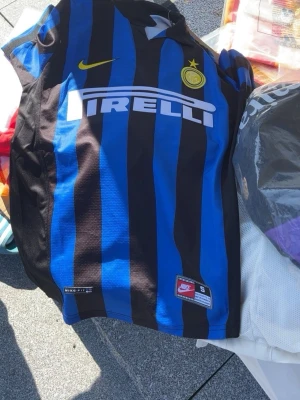 Inter Ronaldo matchtröja Nike S - Säljer en klassisk Inter Milan matchtröja från Nike i storlek S. Tröjan har blå och svarta ränder, gult Nike-märke, Inter-logga och Pirelli som sponsor. På ryggen står det Ronaldo och nummer 9. Perfekt för fotbollsfans!