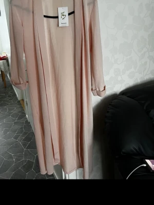 Ljusrosa lång morgonrock Busem - Säljer en tunn och elegant ljusrosa morgonrock från Busem. Modellen är lång med långa ärmar och öppen framtill utan knytband. Materialet är lätt och transparent, perfekt för en chill morgon eller kväll hemma.  Oanvänd 