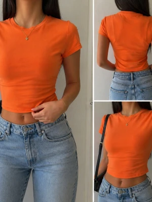 Orange croppad t-shirt - Trendig orange croppad t-shirt med rund hals och korta ärmar. Enkel och stilren design som passar perfekt till jeans eller kjol. Gjord i mjukt material för en bekväm känsla hela dagen.
