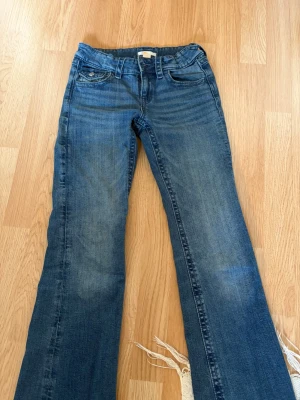 Blå bootcut jeans från Gina Tricot - Snygga blå bootcut jeans från Gina Tricot med klassisk femficksdesign och lätt slitna detaljer. Jeansen har normalhög midja och är tillverkade i denim med en skön stretch. Perfekta för dig som gillar en avslappnad men trendig look.