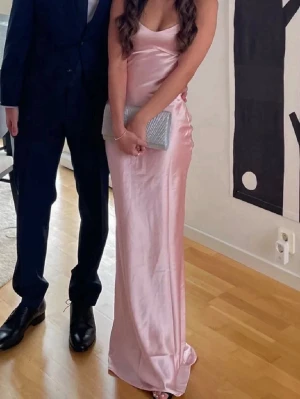 Ljusrosa långklänning i satin - En ljusrosa långklänning i satin med smala axelband som går att knyta som man vill! Perfekt till 9ans eller student bal, aldrig använd💗Lånade bilder!