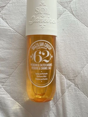 Sol de Janeiro Brazilian Crush 62 mist - En parfymmist från Sol de Janeiro med doft av pistage och salt karamell. Flaskan är genomskinlig med gul ton och har ett vitt lock med präglad logga. Perfekt för dig som gillar söta och krämiga dofter.