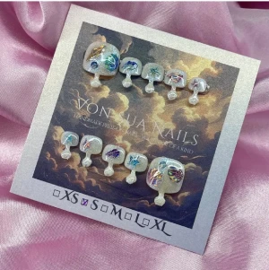 Shelly (S);Square Toe - Unika tå-press-on naglar i storlek S: 14 mm, 9 mm, 9,5 mm, 9 mm, 6 mm. Naglarna har en mjölkvit bas med  skimrande dekorationer i blått, grönt och lila samt detaljer som snäckor och stjärnor. Perfekt för dig som vill ha ett kreativt och färgstarkt nagelset. Handgjorda och riktigt detaljerade.