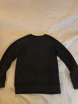 Svart sweatshirt Peak Performance - Svart sweatshirt från Peak Performance med diskret logga broderad på bröstet. Klassisk rund halsringning, långa ärmar och ribbade muddar vid ärmslut och nederkant. Perfekt för en avslappnad och stilren look.