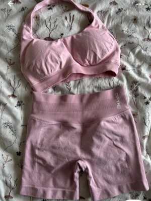 DFYNE IMPACT - ljusrosa set - Rosa seamless träningsset från DFYNE med sport-bh och matchande shorts. Bh:n har breda axelband och vadderade kupor, shortsen är midwaist i midjan och har ribbad linning. Jag köpte dessa på Vinted men det passade tyvärr inte då det var för litet. Säljaren hade använt shortsen ca 5 gånger och var därför lite ljusare i färgen. Jag tyckte inte det var något som syndes utan alls var i superfint skick 💕