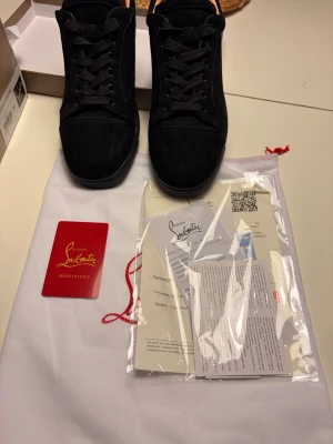 Svarta sneakers från Christian Louboutin - Snygga svarta sneakers från Christian Louboutin i mocka med klassisk låg siluett. Skorna har svarta skosnören, rund tå och diskreta sömdetaljer. Insidan är ljusbeige och de kommer med originalpåse och certifikat. Har haft på mig dem fotal gånger men säljer för att dem är förstora. Vi kan diskutera pris. 